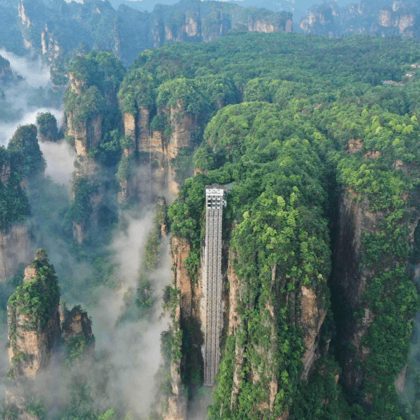 Aerial view of Bailong Elevator amid misty quartz sandstone peaks in Zhangjiajie National Forest Park