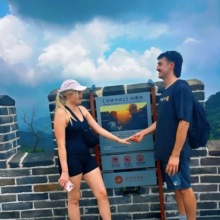 Couple holding hands at the Filming Location of If You Are the One II sign on Mutianyu Great Wall near Beijing