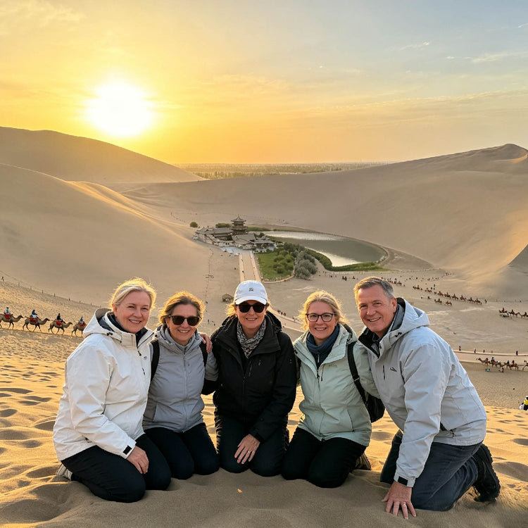 Group of travelers posing on sand dunes at Mingsha Mountain during sunset
