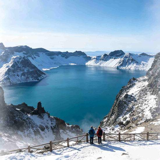 Heavenly Lake of Changbai Mountain, turquoise crater lake surrounded by snow peaks with visitors on the viewing platform