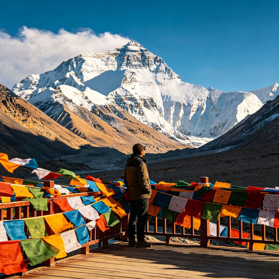Traveler viewing Himalayan peaks at a viewpoint with colorful Tibetan prayer flags