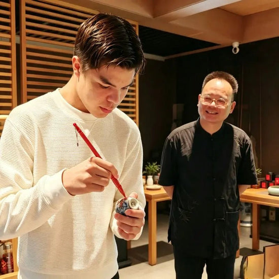 Young guest hand-painting a zodiac Ru porcelain teacup during Chinese tea culture experience