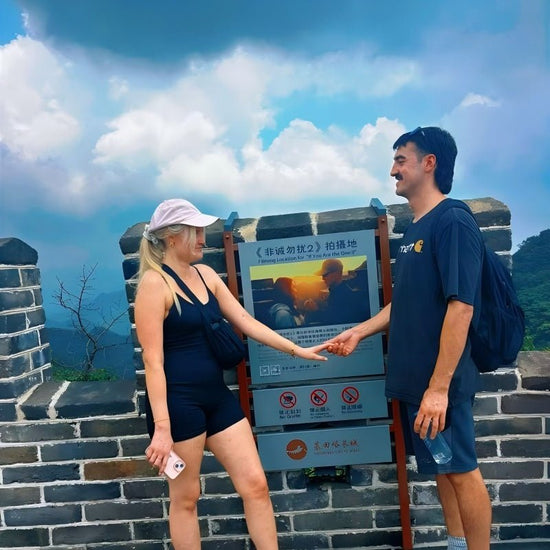 Couple holding hands at the Filming Location of If You Are the One II sign on Mutianyu Great Wall near Beijing