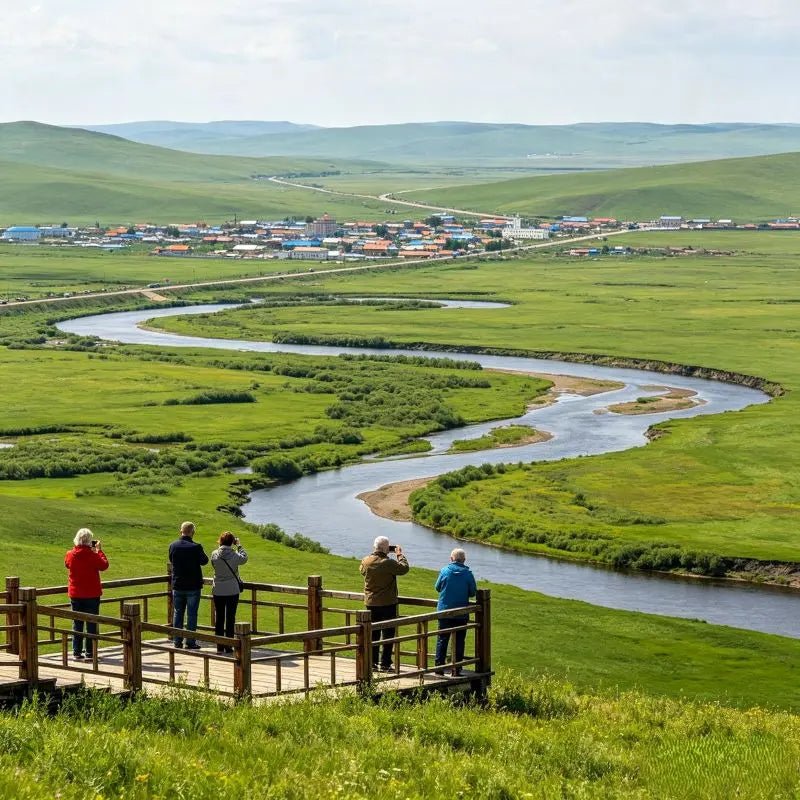 Overlook of winding river across green grassland, western tourists on viewing platform at Morigele River scenic area