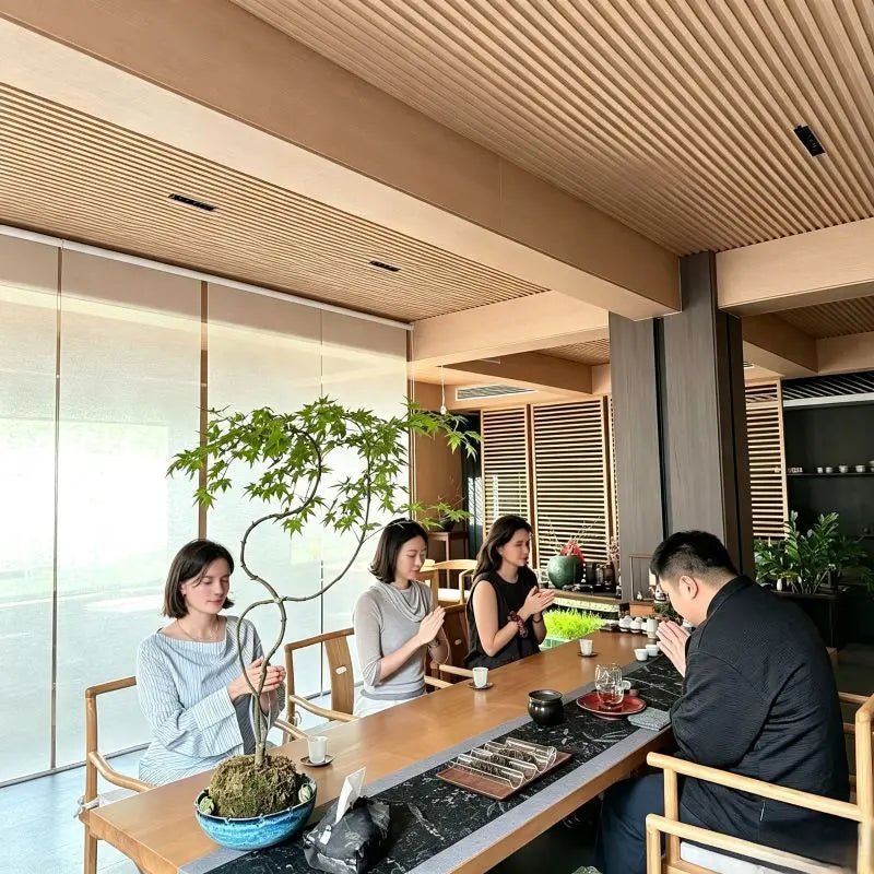 Intimate tea ceremony session with guests seated along the table in a tranquil hutong space