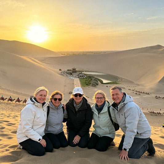 Group of travelers posing on sand dunes at Mingsha Mountain during sunset