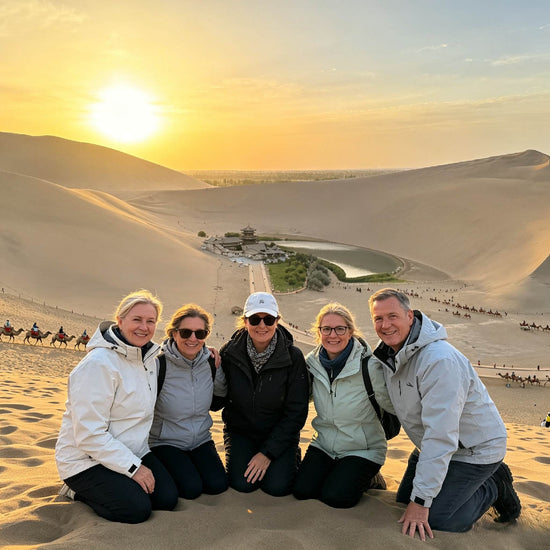 Group of travelers posing on sand dunes at Mingsha Mountain during sunset