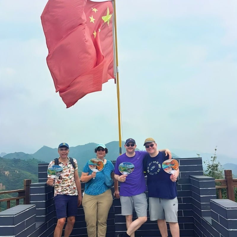 Group of happy travelers posing inside a Great Wall watchtower with Chinese national flag waving at Mutianyu Great Wall near Beijing